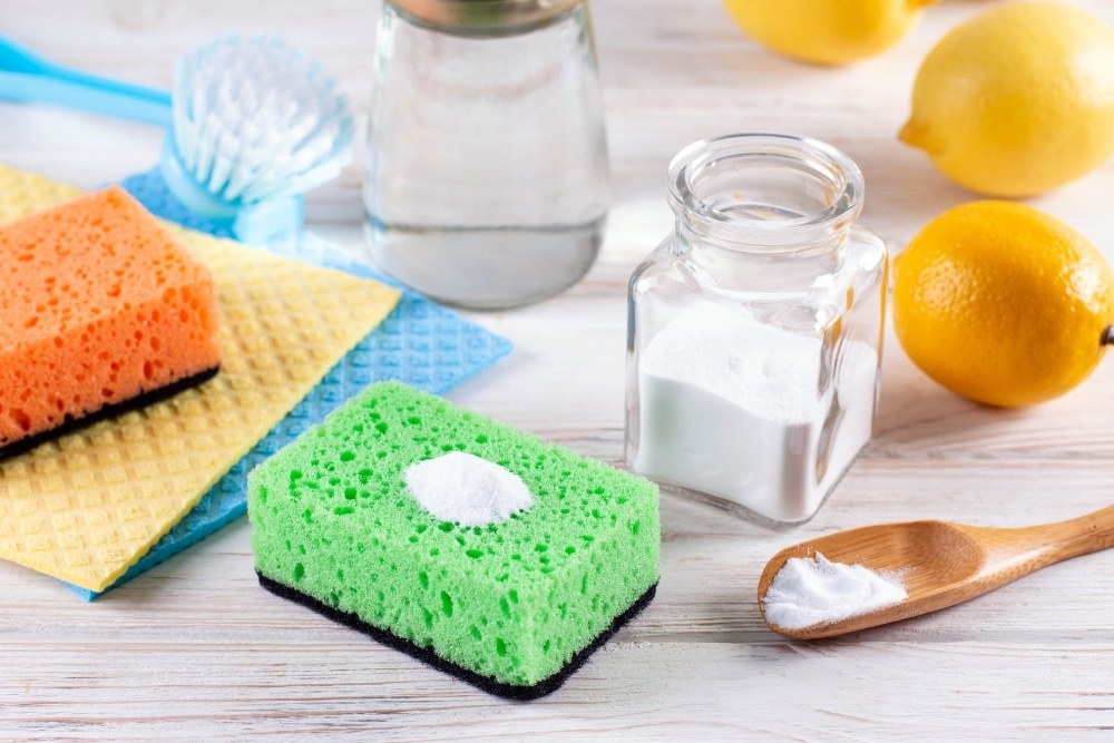 Bicarbonate of soda, lemons and cleaning sponges laid out on a kitchen bench