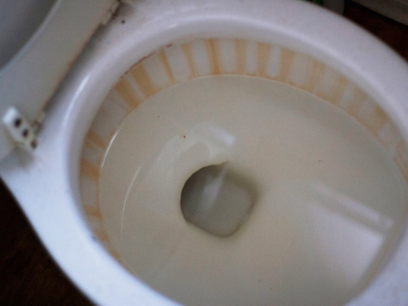 Stained toilet bowl with water backup needing fixing a blocked toilet