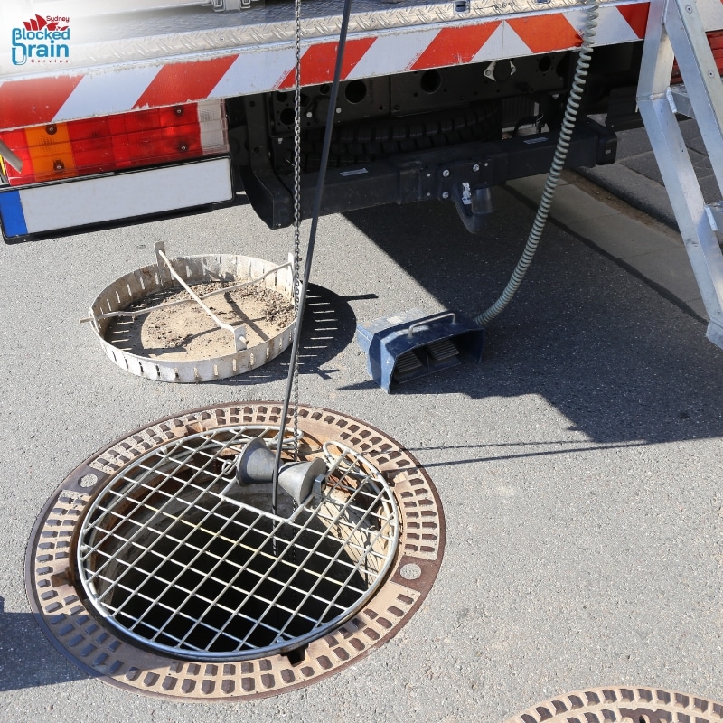 Sewer camera technology locates drain issues as inspection device is lowered into a manhole from a service truck.