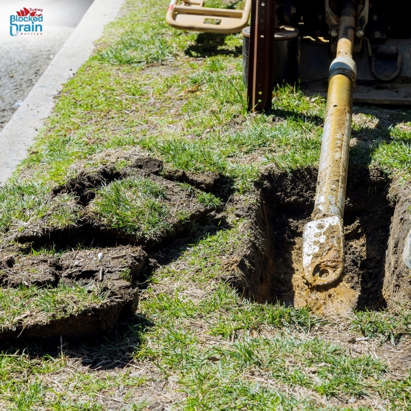 Pipe relining Sydney showing trenchless drilling equipment in freshly dug lawn for underground pipe repair work