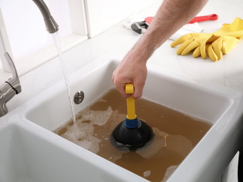 Plunging kitchen sink full of dirty water — indoor causes of blocked drains.