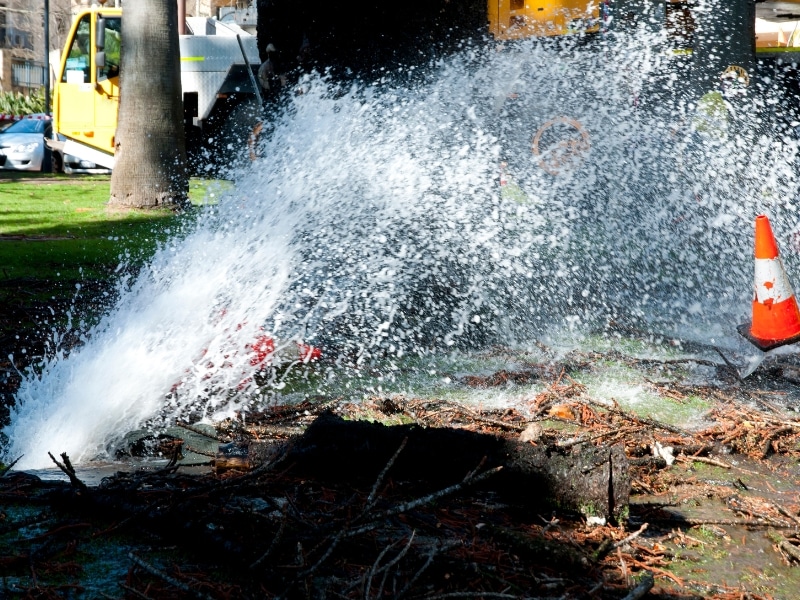 Damaged underground pipe spraying water after sewer eel misuse during drain cleaning.