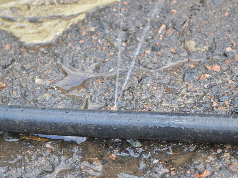 Leaking outdoor pipe showing water spray increasing pipe relining cost